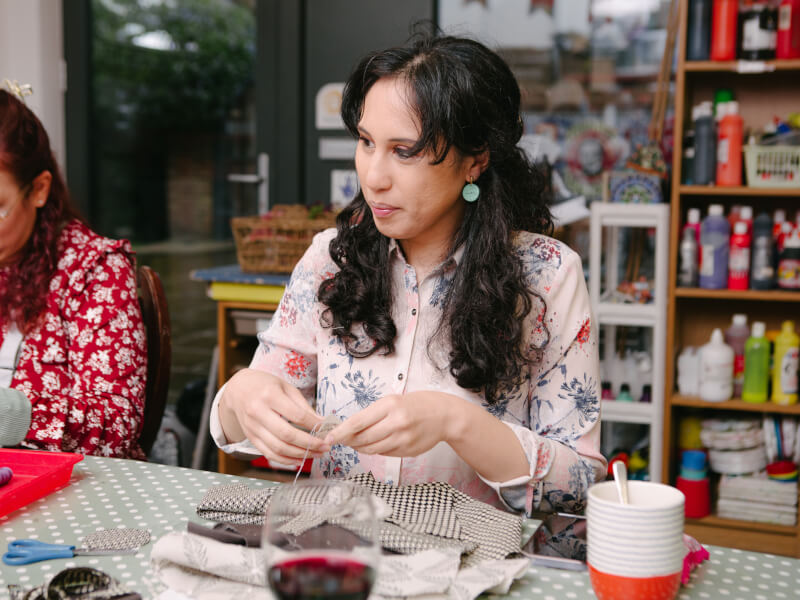 Two smiling women sewing fabric